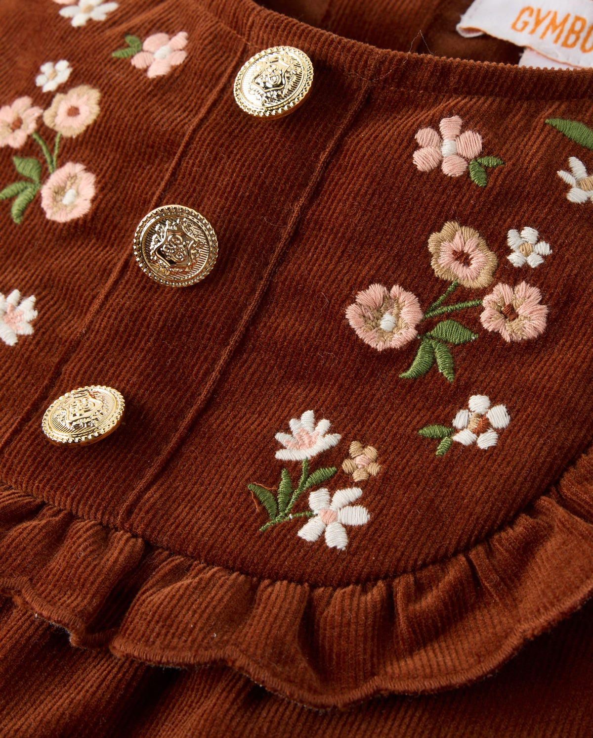 Detalle del canesú festoneado con flores bordadas y botones dorados del vestido Gymboree pana marrón